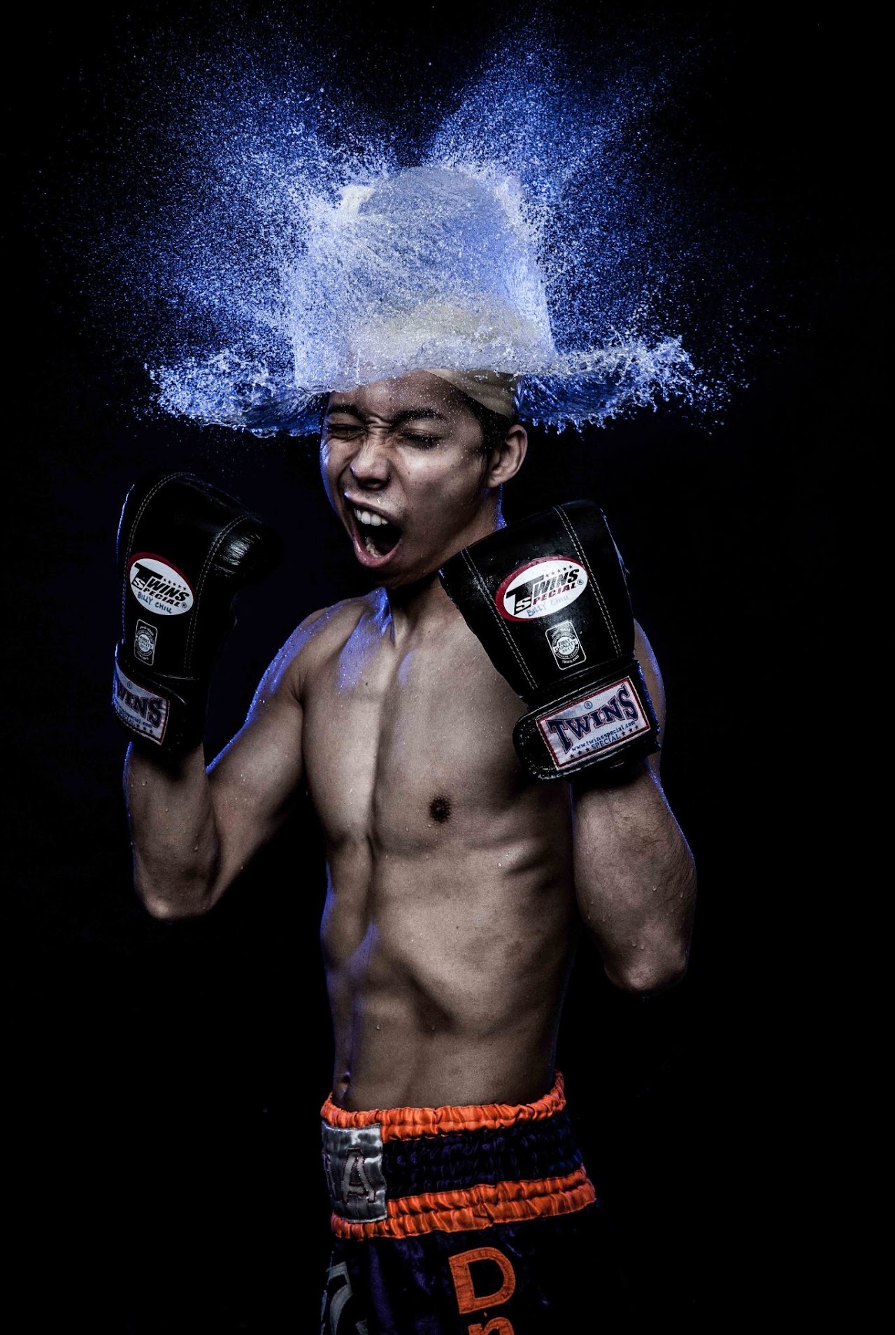 Boxer wearing gloves as water explodes over his head like a crown.