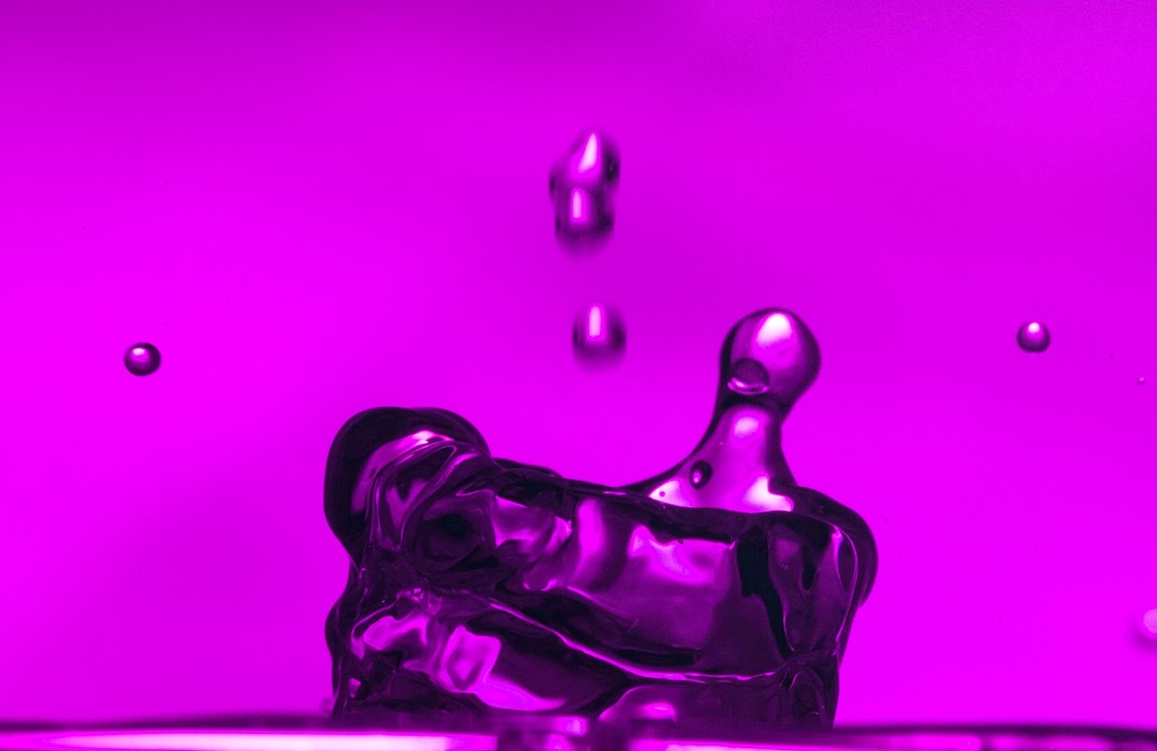Magenta liquid column with small droplets suspended in a saturated pink field.