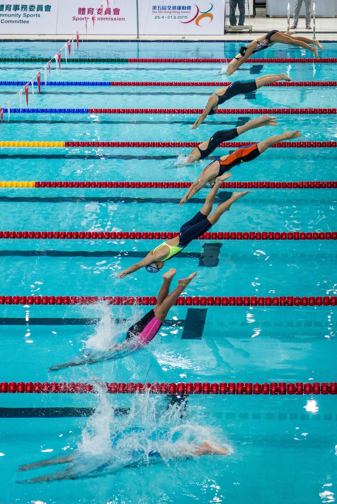 Swimmers diving into lanes in a vertical sequence.