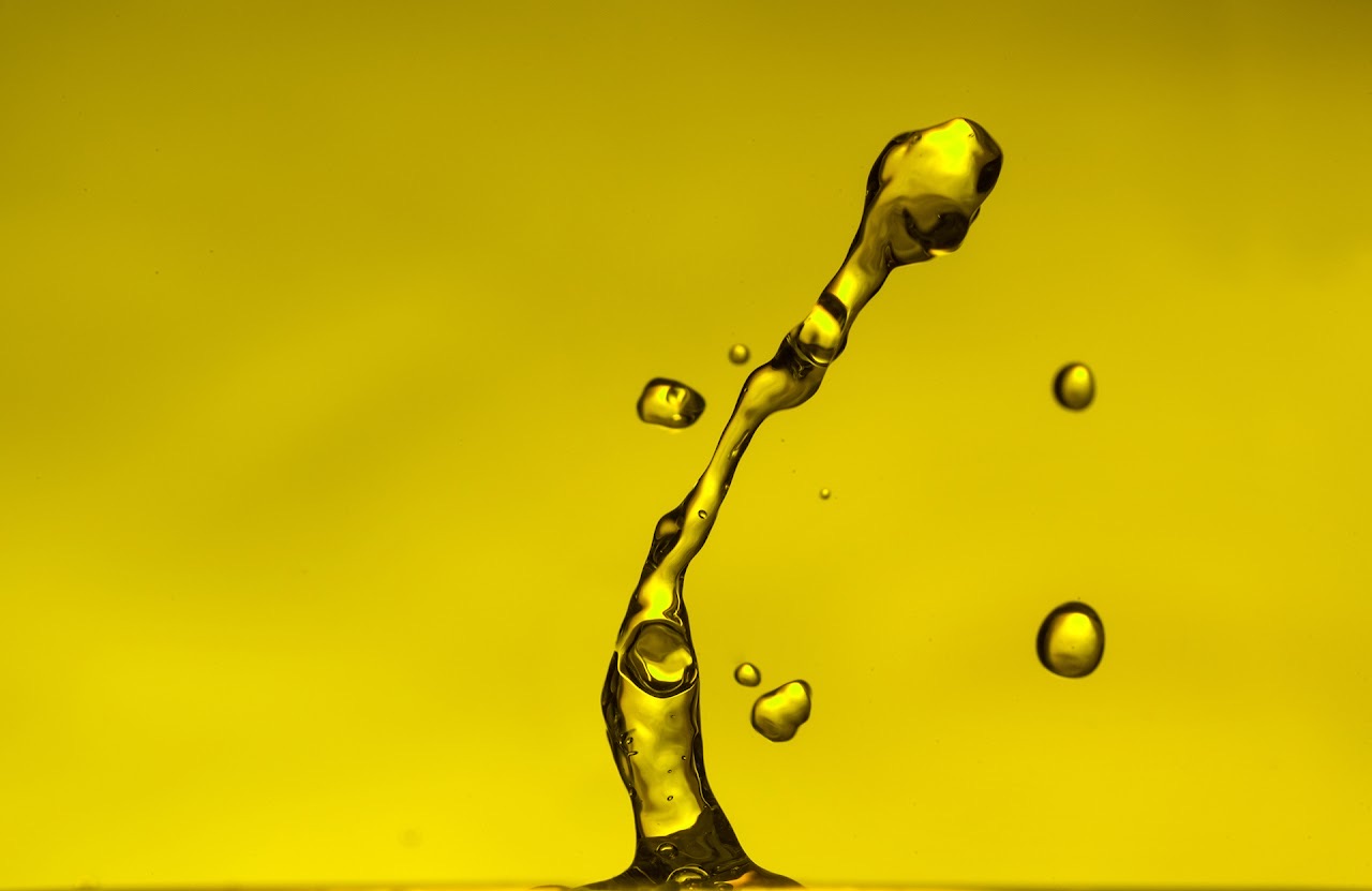 Yellow water arc with droplets suspended mid-air.