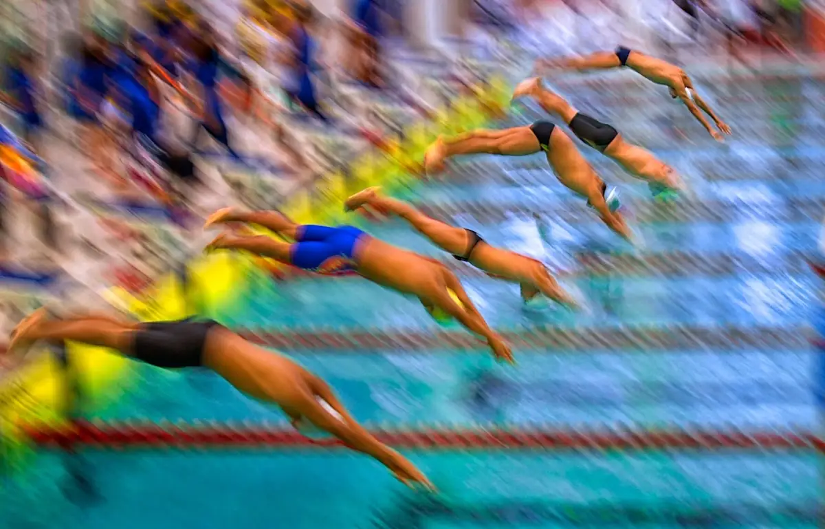 Divers streaking in motion over a swimming pool.