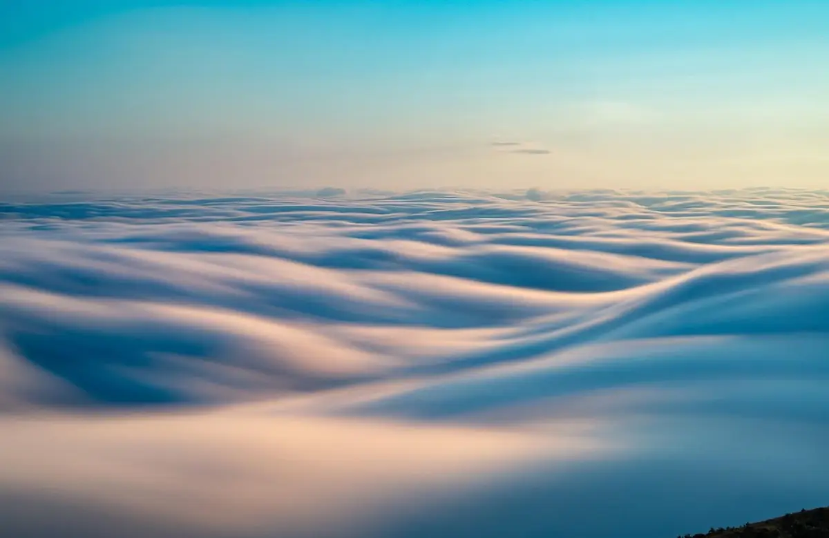 A calm pastel sea of clouds at dawn.