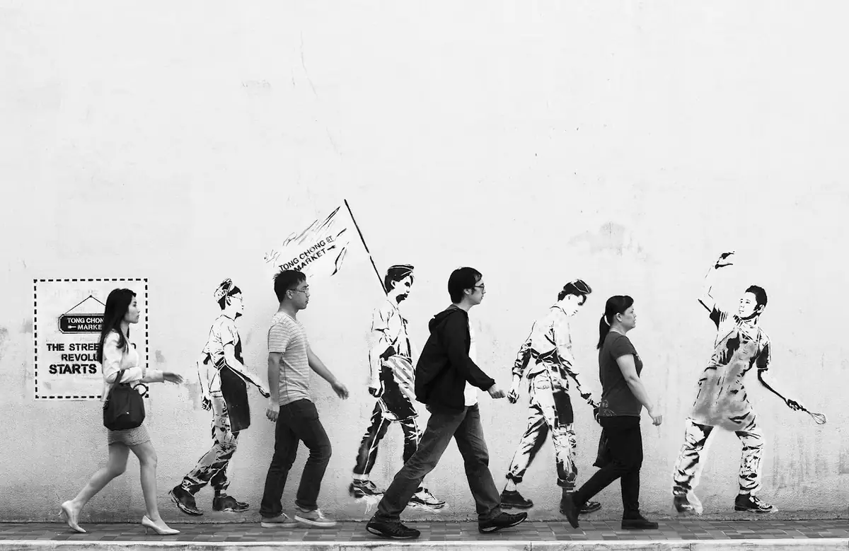 Pedestrians beside street art.