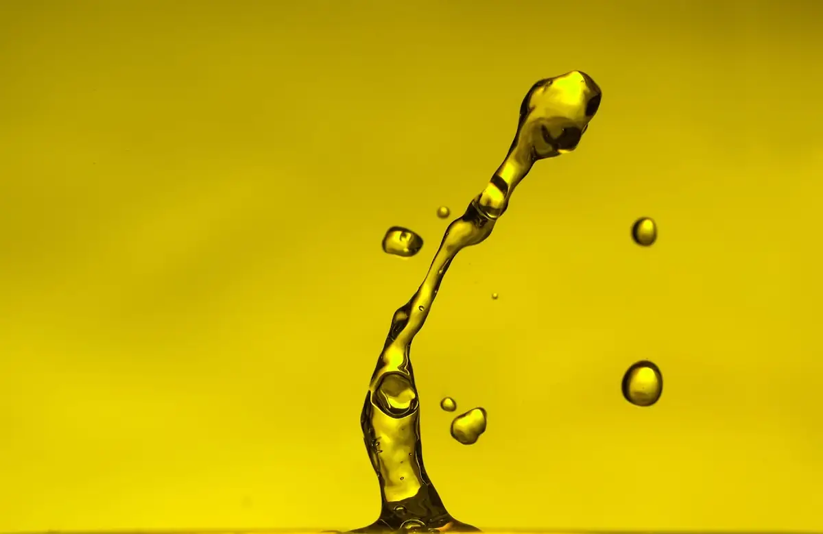 Yellow water arc with droplets suspended mid-air.