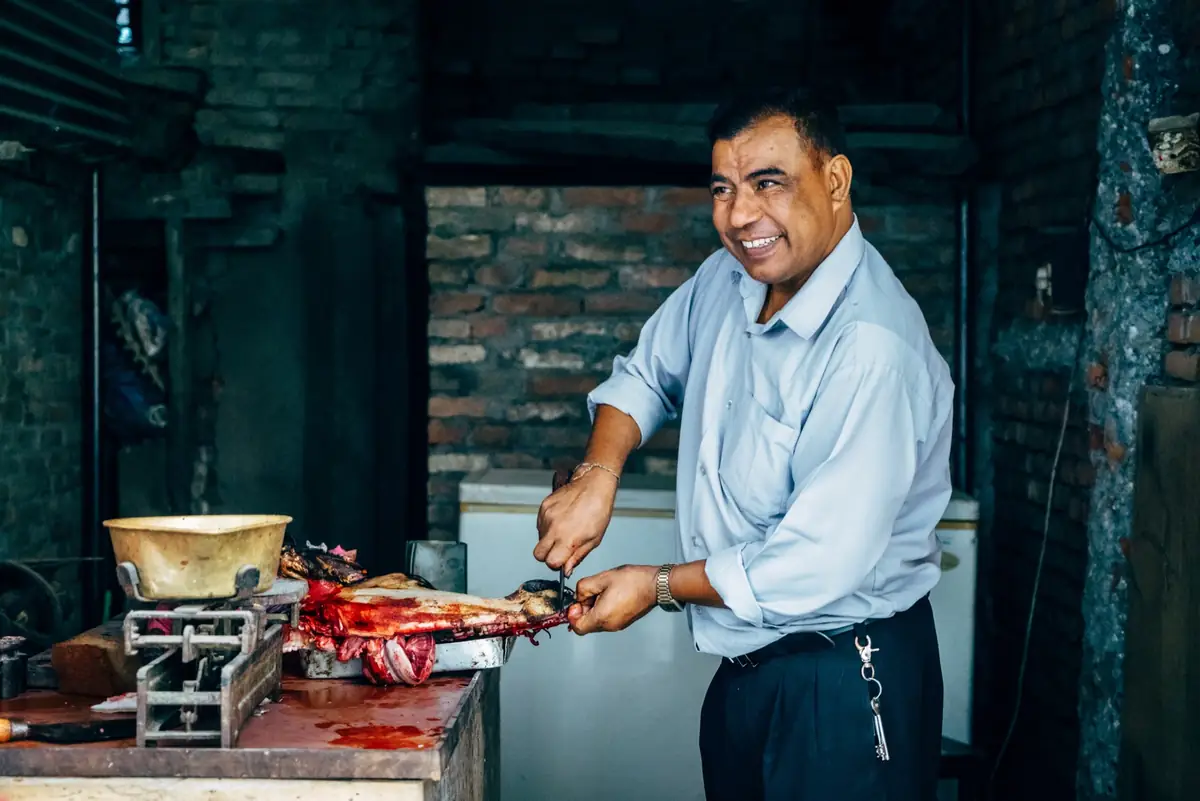 Man cooking skewers in a small kitchen.