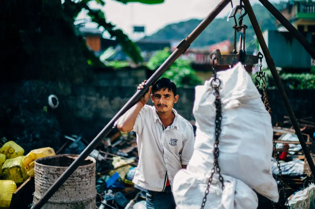 Man working with a suspended sack at a market.