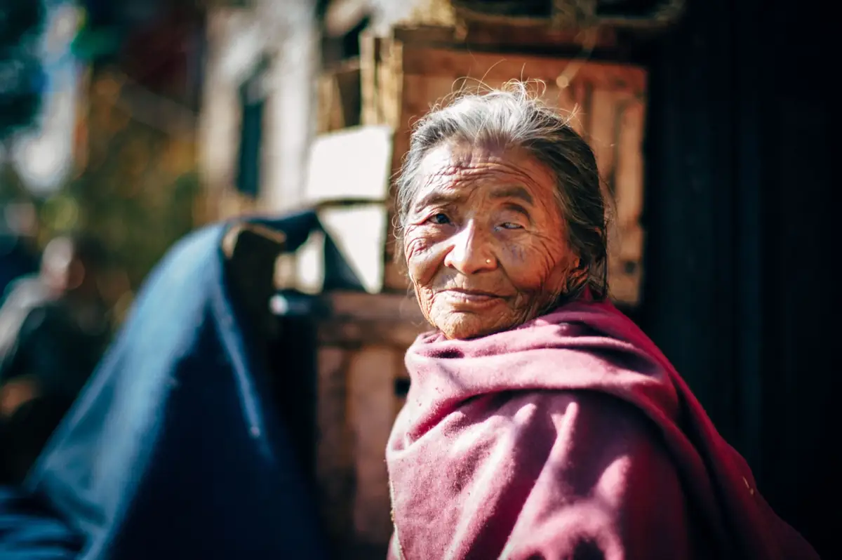 Elderly woman in pink clothing looking toward the camera.