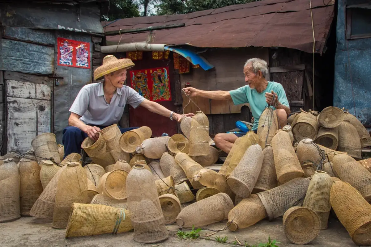 Two people sitting among many woven baskets.