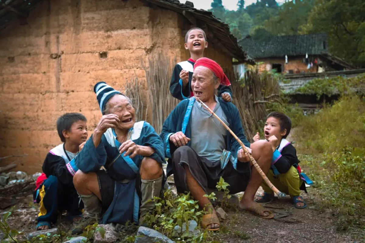 Elders and children laughing in a village setting.